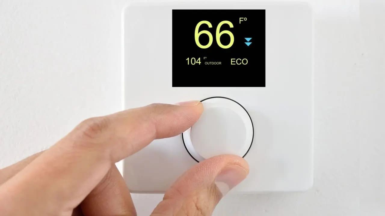 A person is adjusting the temperature on an electronic thermostat.